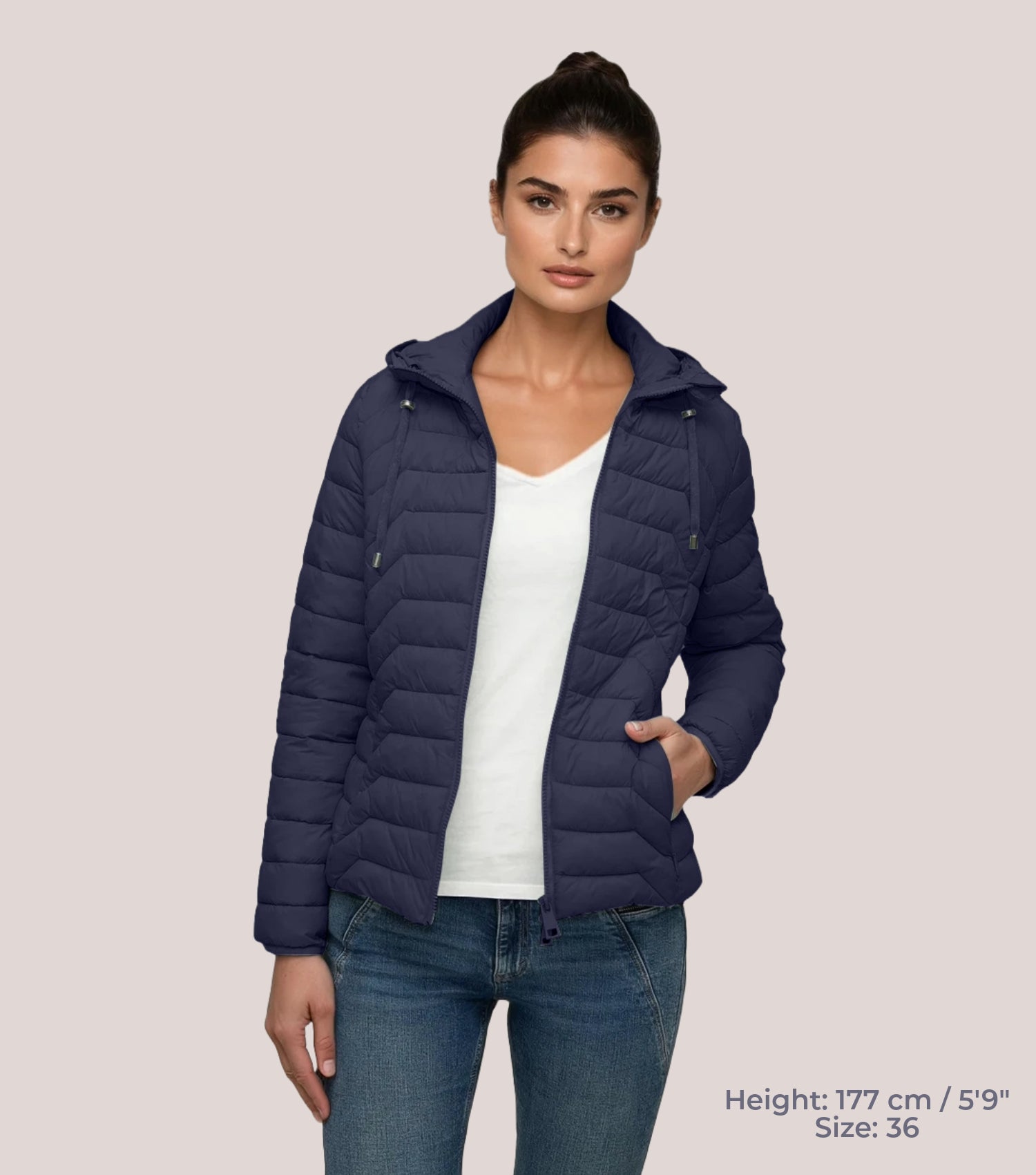 Frau mit blauer Steppjacke und weißem T-shirt. Modell ist 177cm groß und trägt Größe 36.