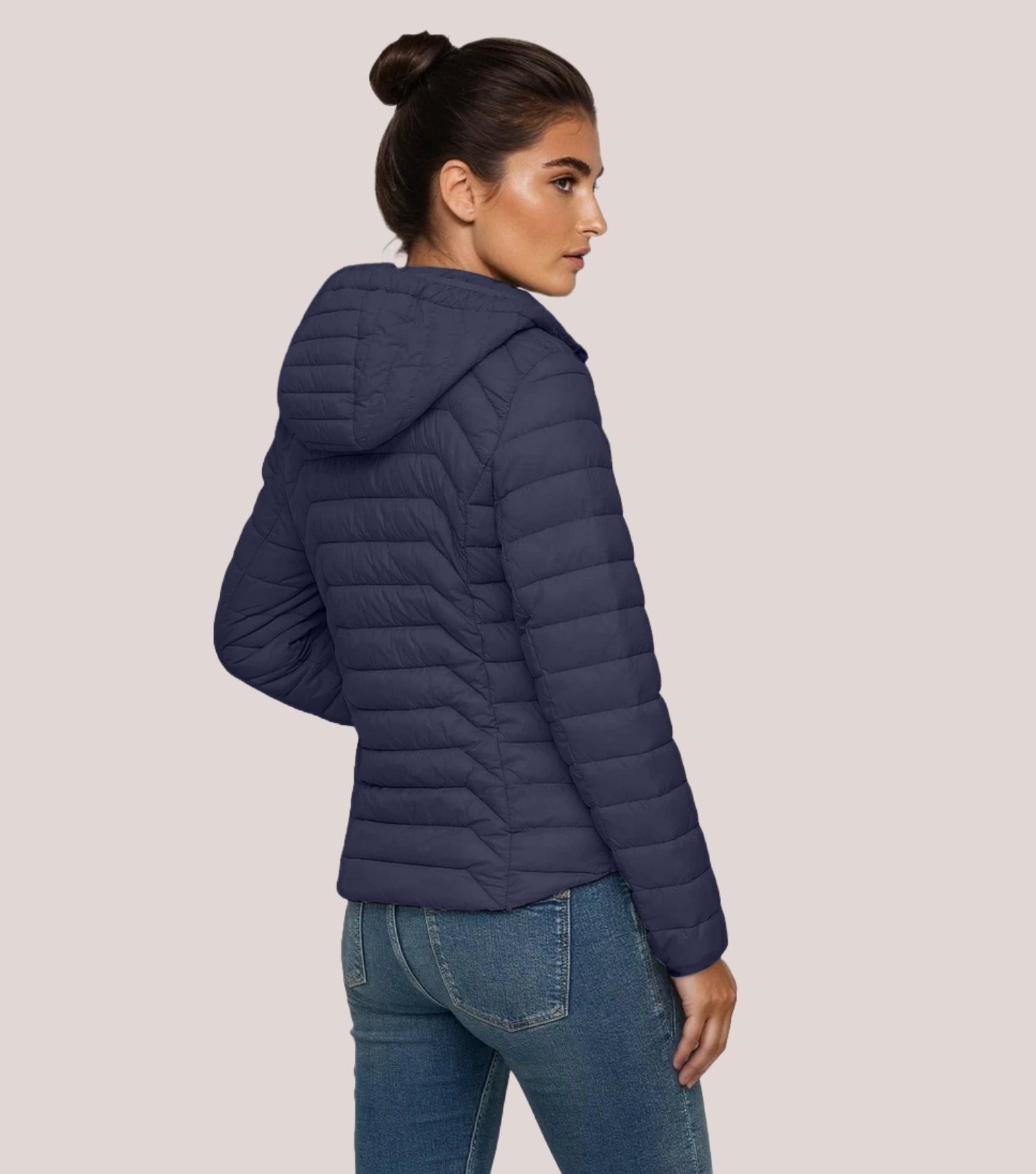 Rückansicht Frau mit blauer Steppjacke und weißem T-shirt.
