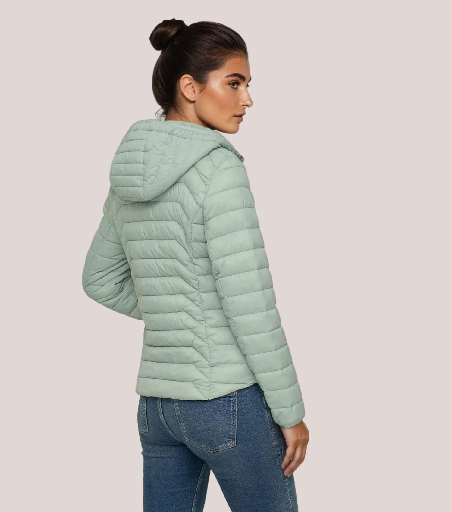 Rückansicht Frau mit grüner Steppjacke und weißem T-shirt.