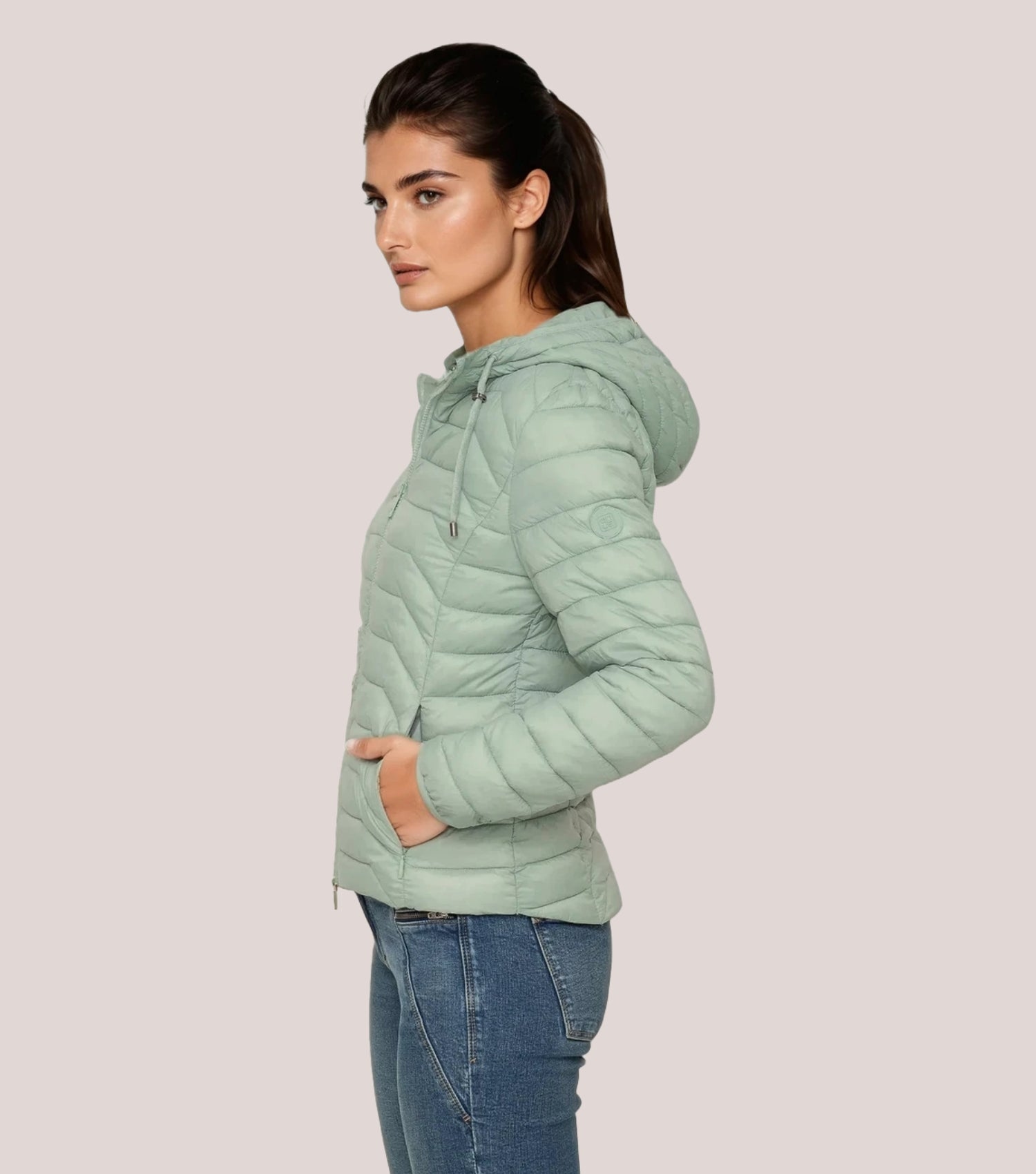 Seitenansicht Frau mit grüner Steppjacke und weißem T-shirt.