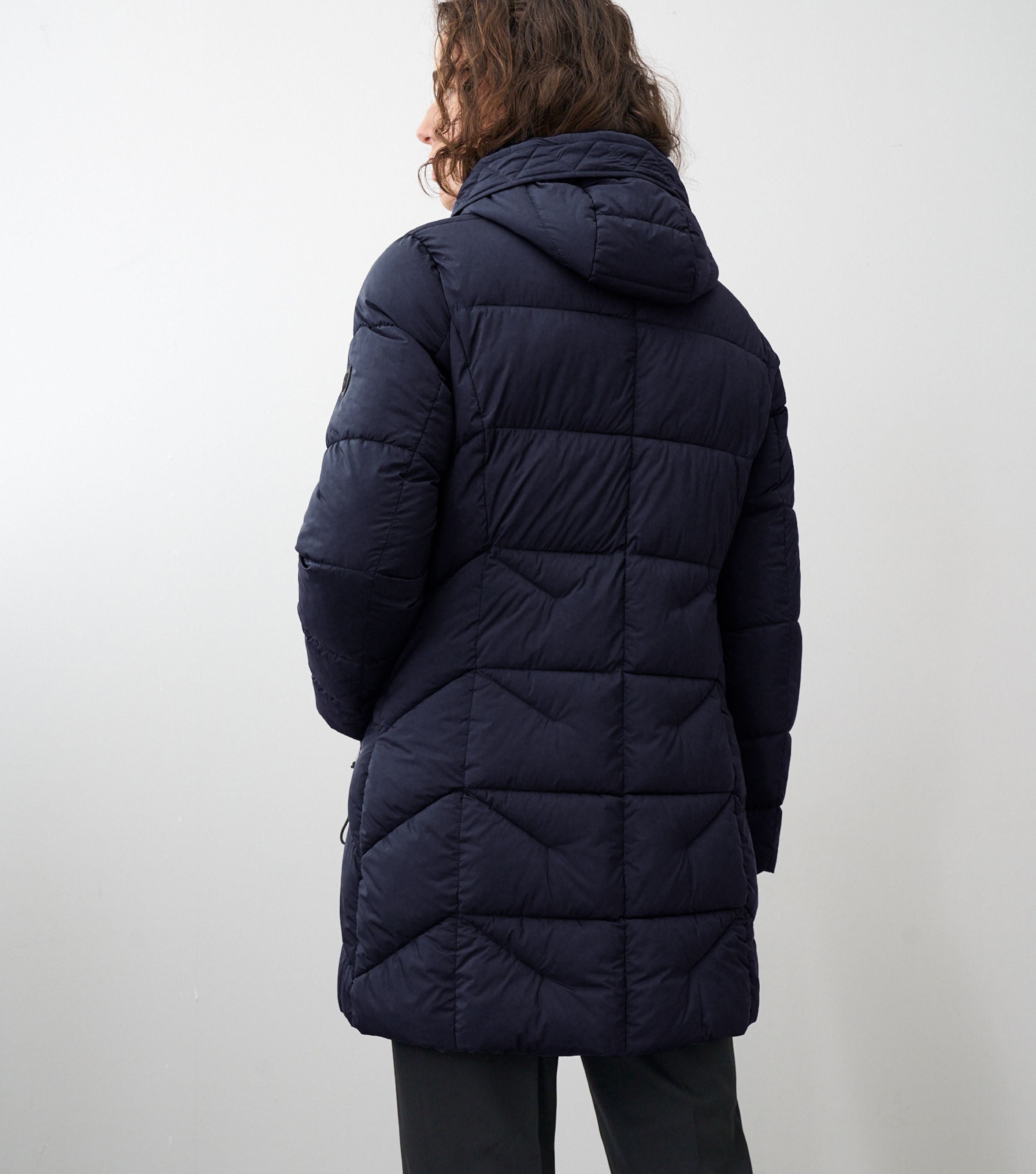 Rückansicht einer braunhaarigen Frau mit einer blauen Winterjacke