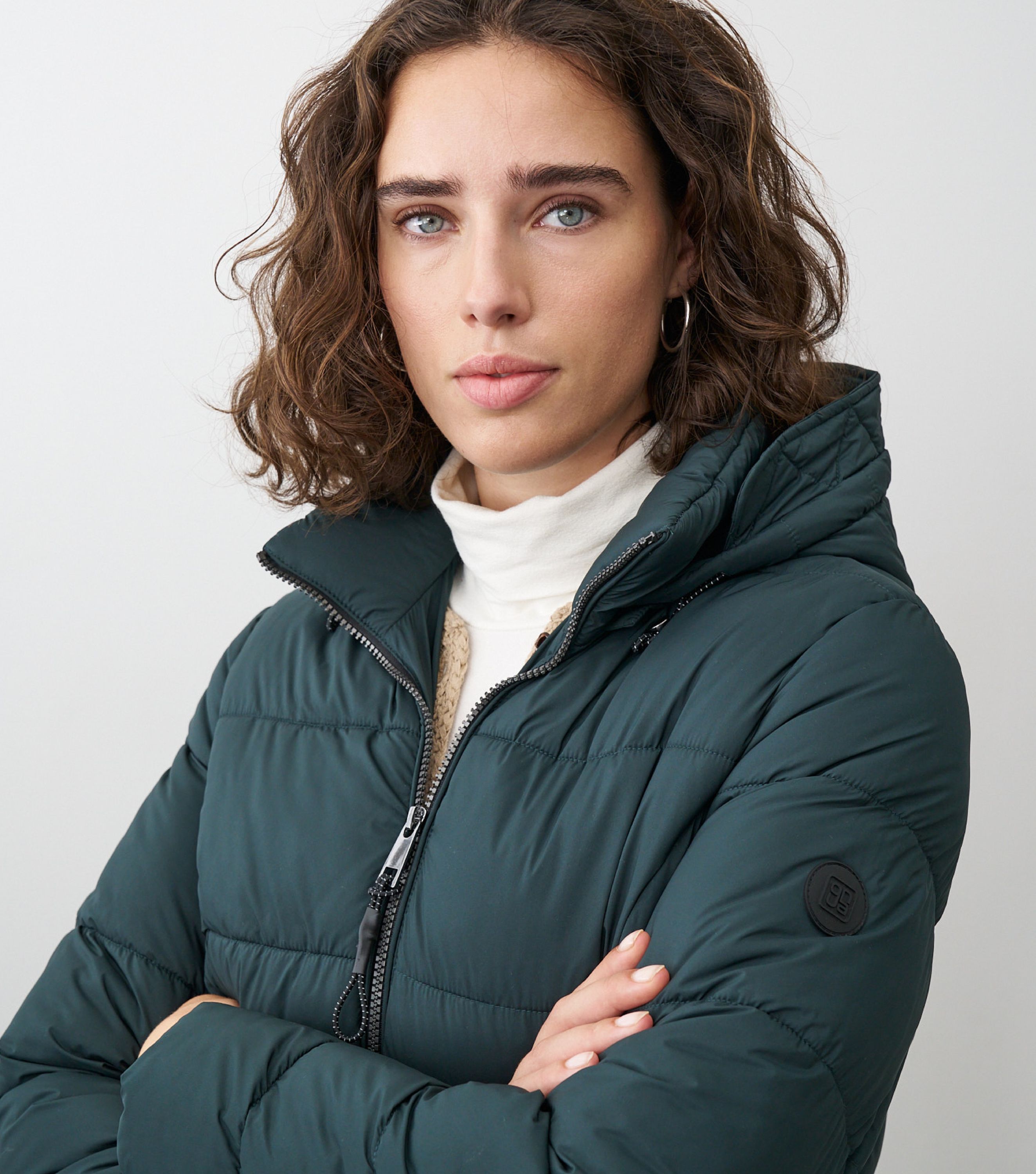 Braunhaarige Frau steht frontal zur Kamera mit grüner Winterjacke