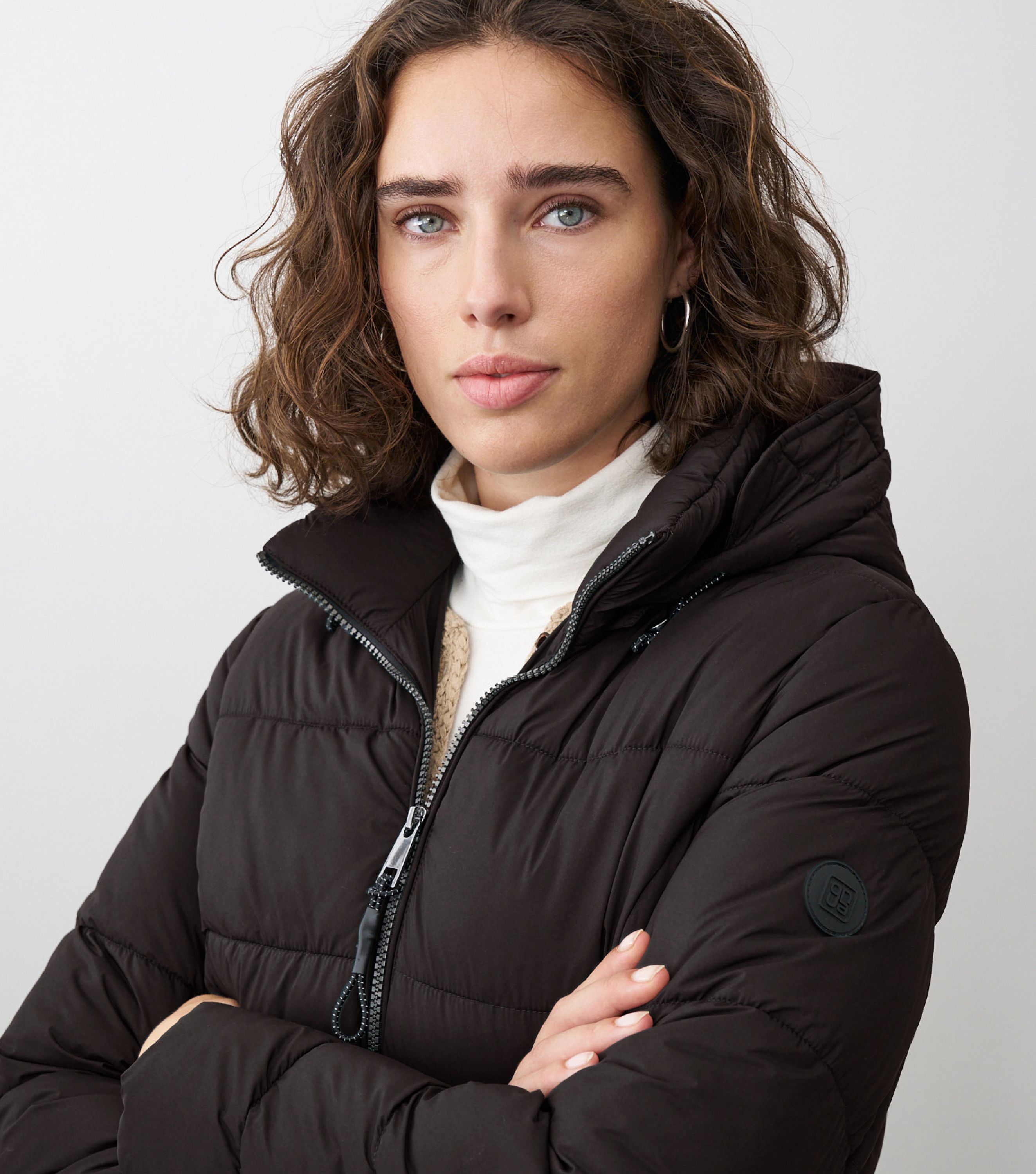 Braunhaarige Frau steht frontal zur Kamera mit schwarzer Winterjacke