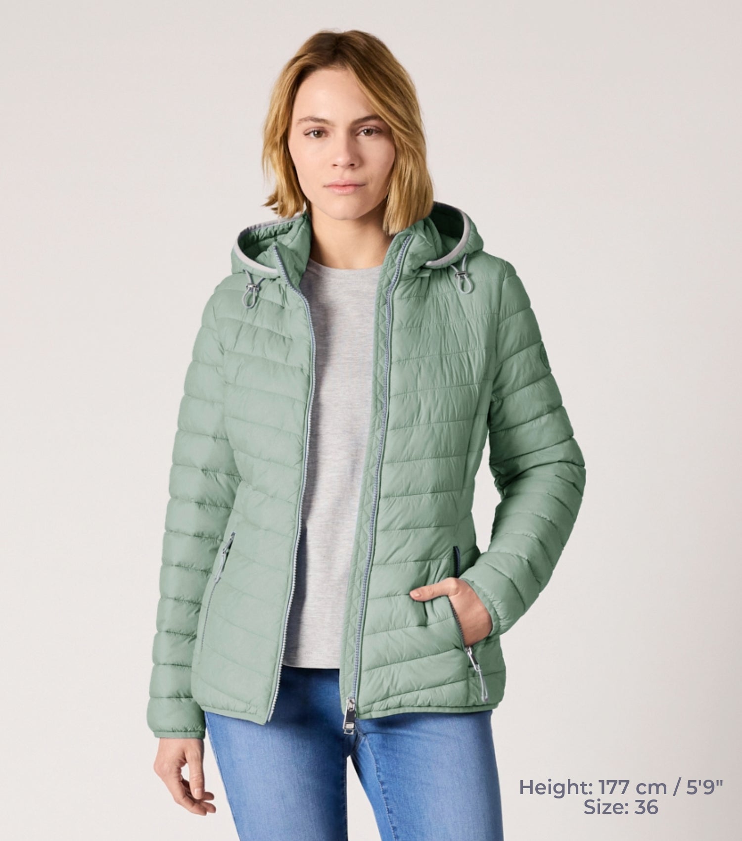 Frau mit grüner Steppjacke und weißem T-shirt. Modell ist 177cm groß und trägt Größe 36. 