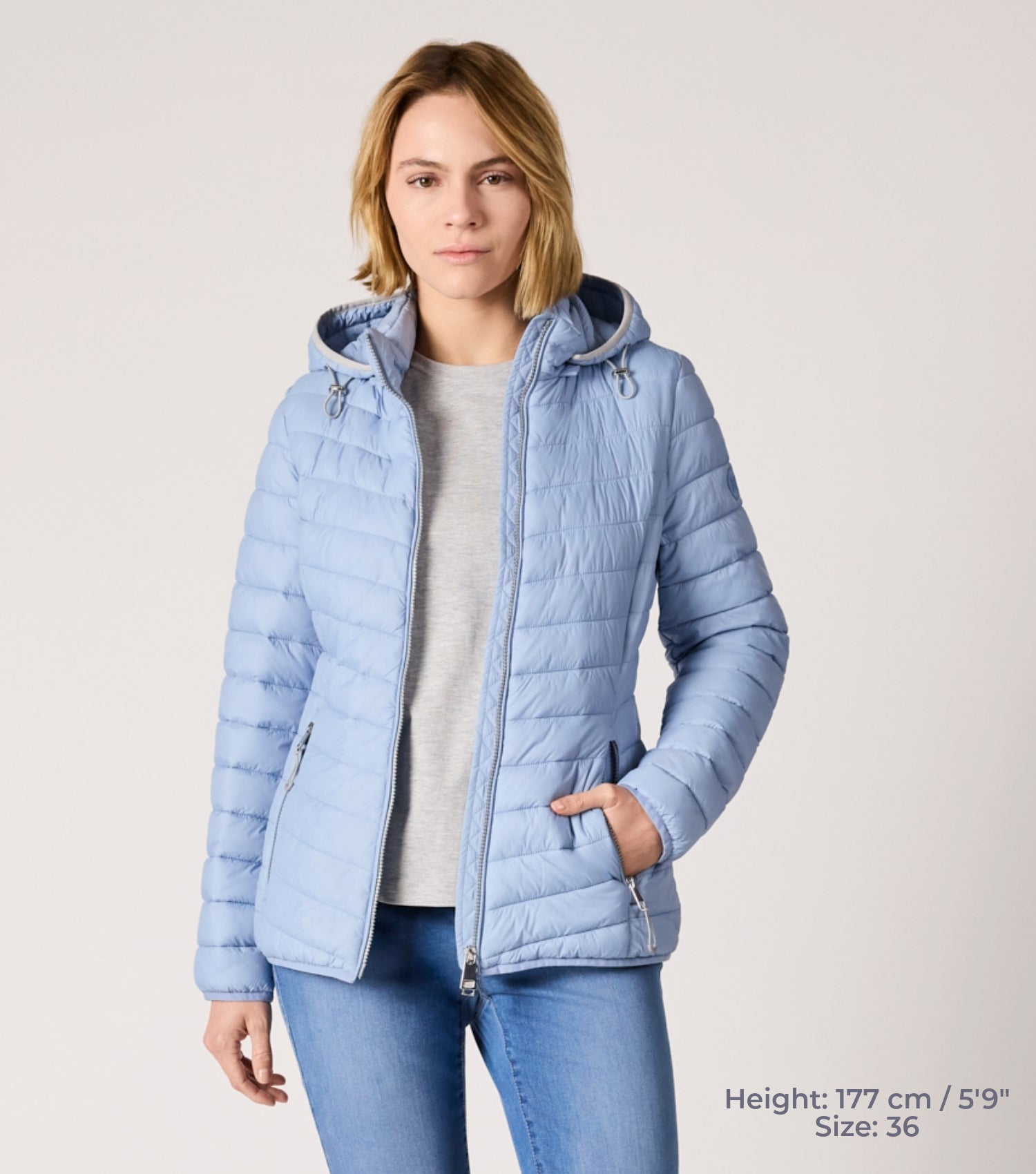 Frau mit hellblauer Steppjacke und weißem T-shirt. Modell ist 177cm groß und trägt Größe 36. 