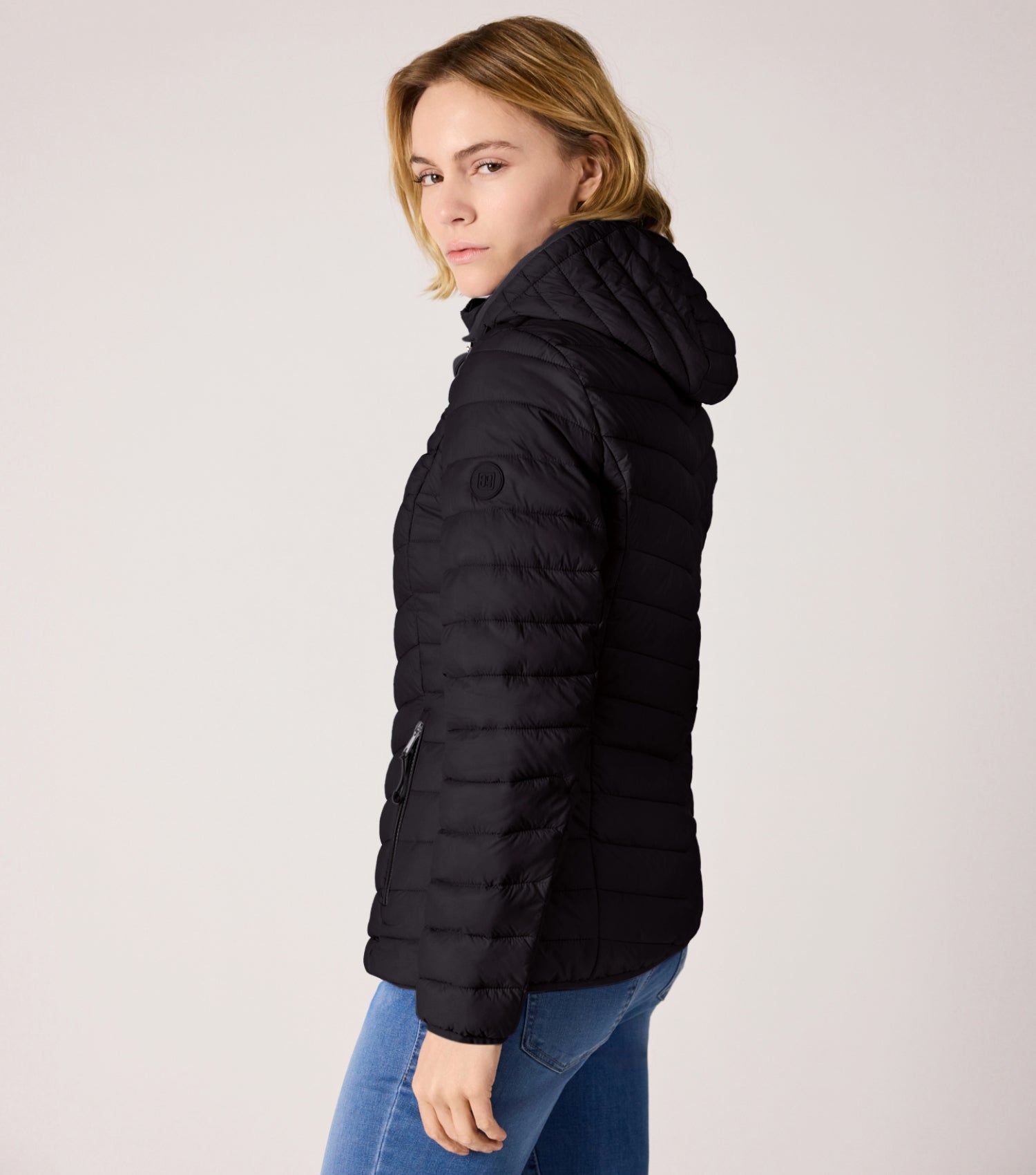 Seitenansicht Frau mit schwarzer Steppjacke und weißem T-shirt.  