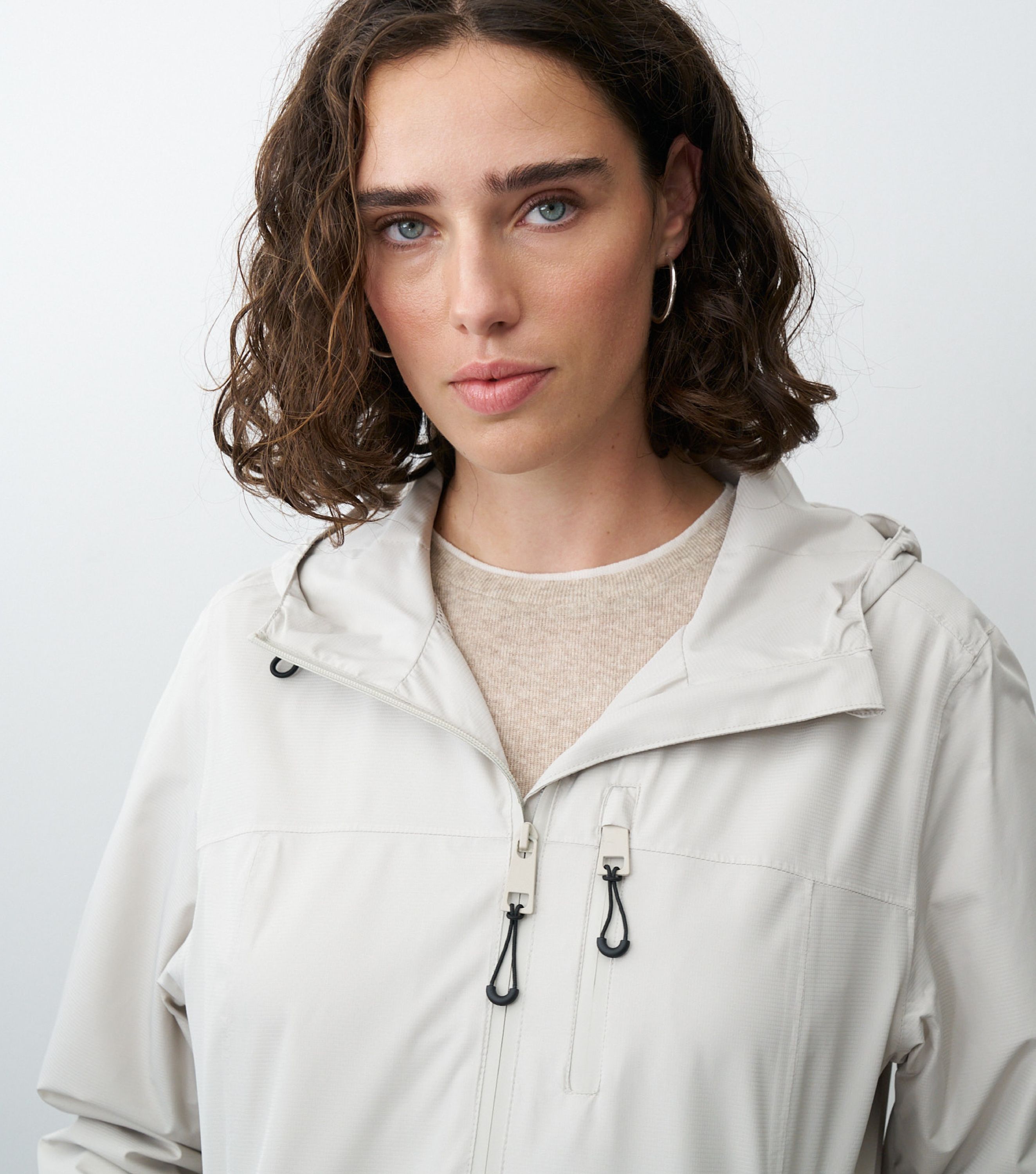 Nahansicht einer braunhaarigen Frau die eine beige Regenjacke trägt 