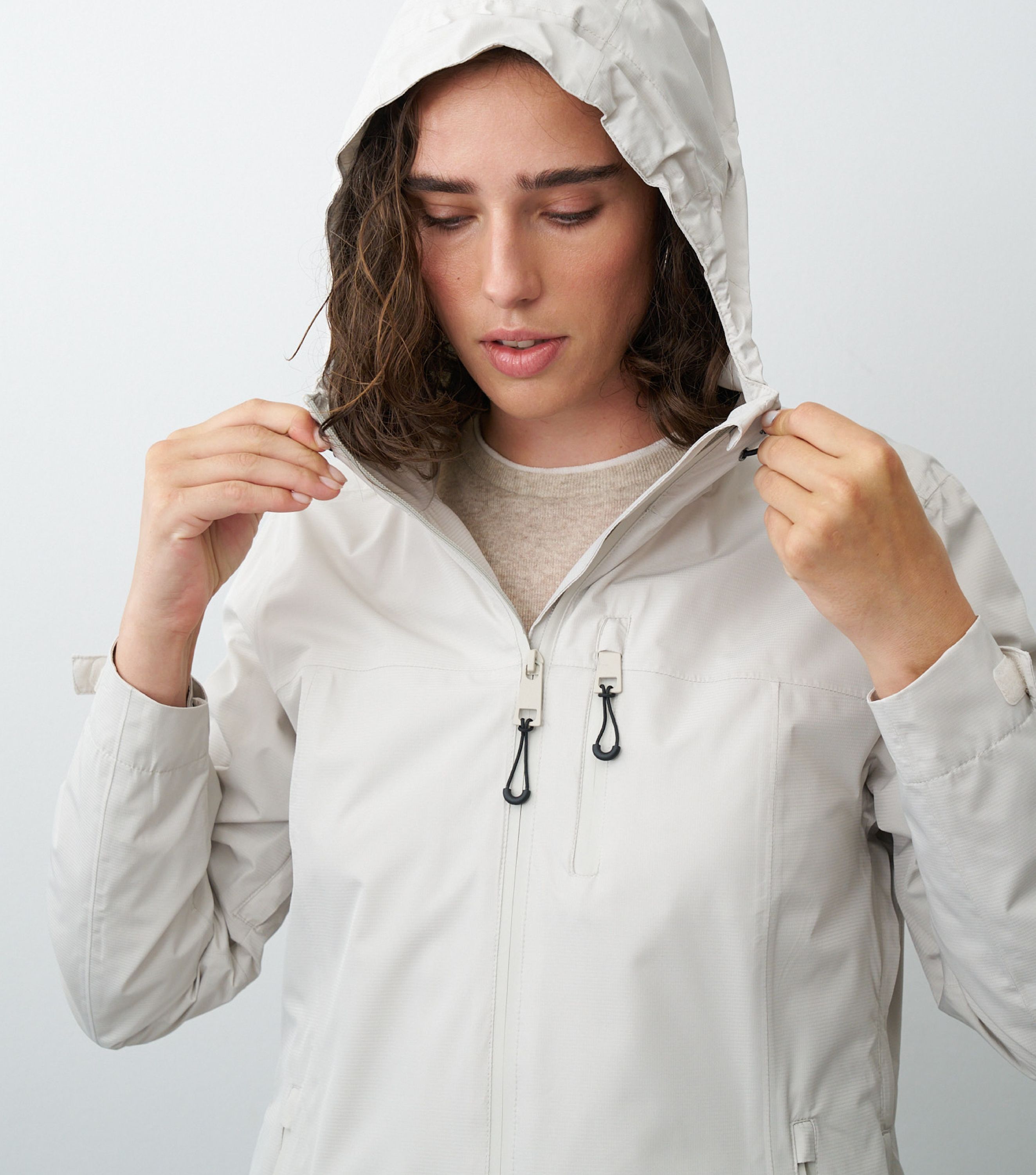 Nahansicht einer Frau die eine beige Regenjacke trägt und die Kapuze aufhat 