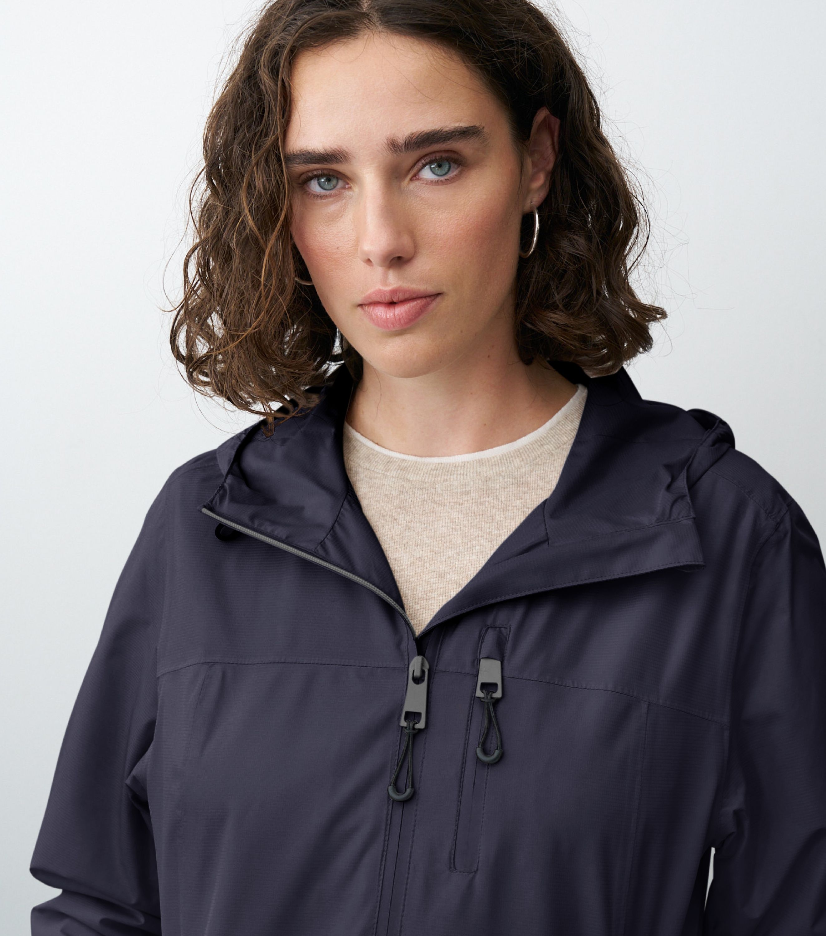 Nahansicht einer braunhaarigen Frau die eine blaue Regenjacke trägt 