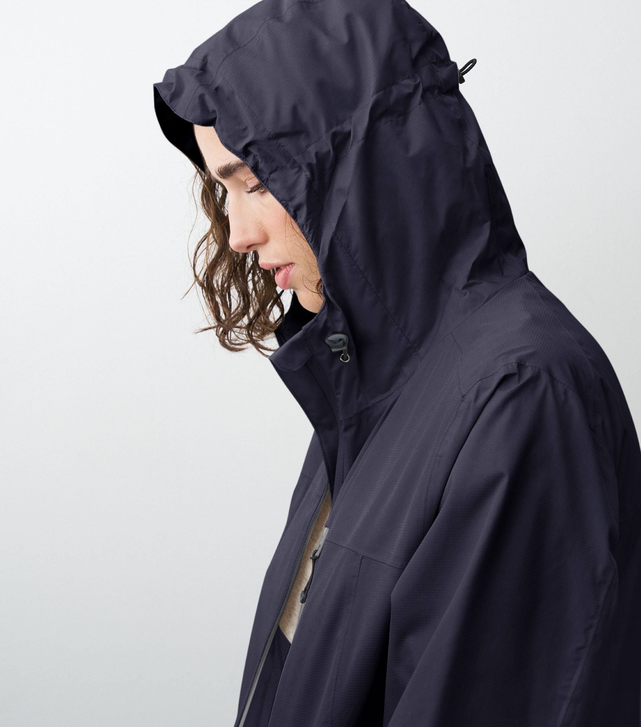 Seitliche Ansicht einer Frau die eine blaue Regenjacke trägt und die Kapuze aufhat 