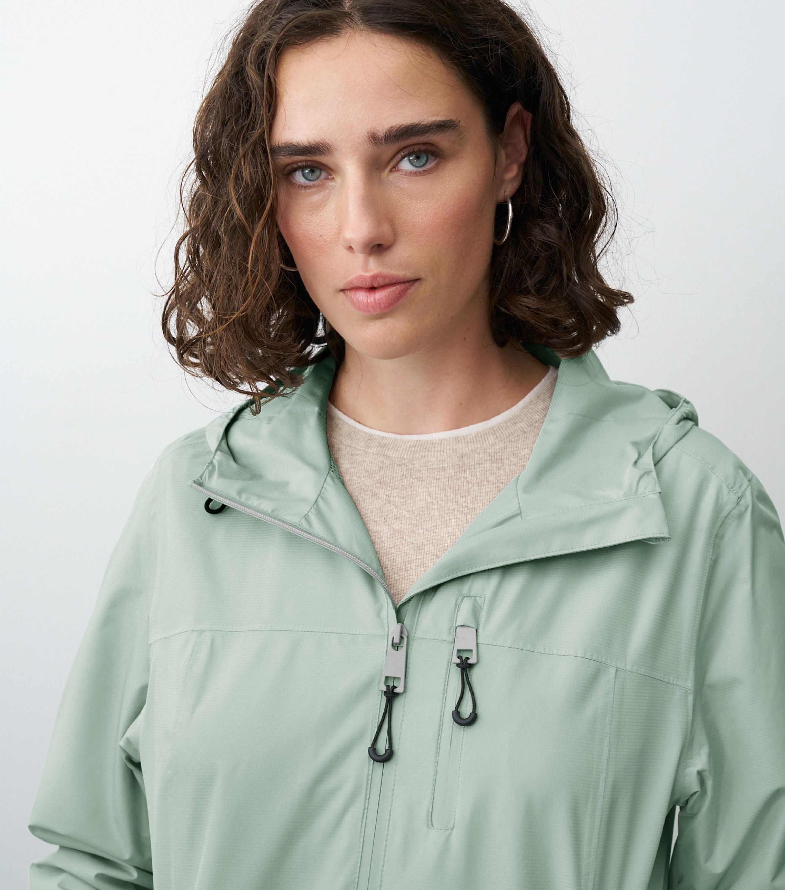 Nahansicht einer braunhaarigen Frau die eine grüne Regenjacke trägt 