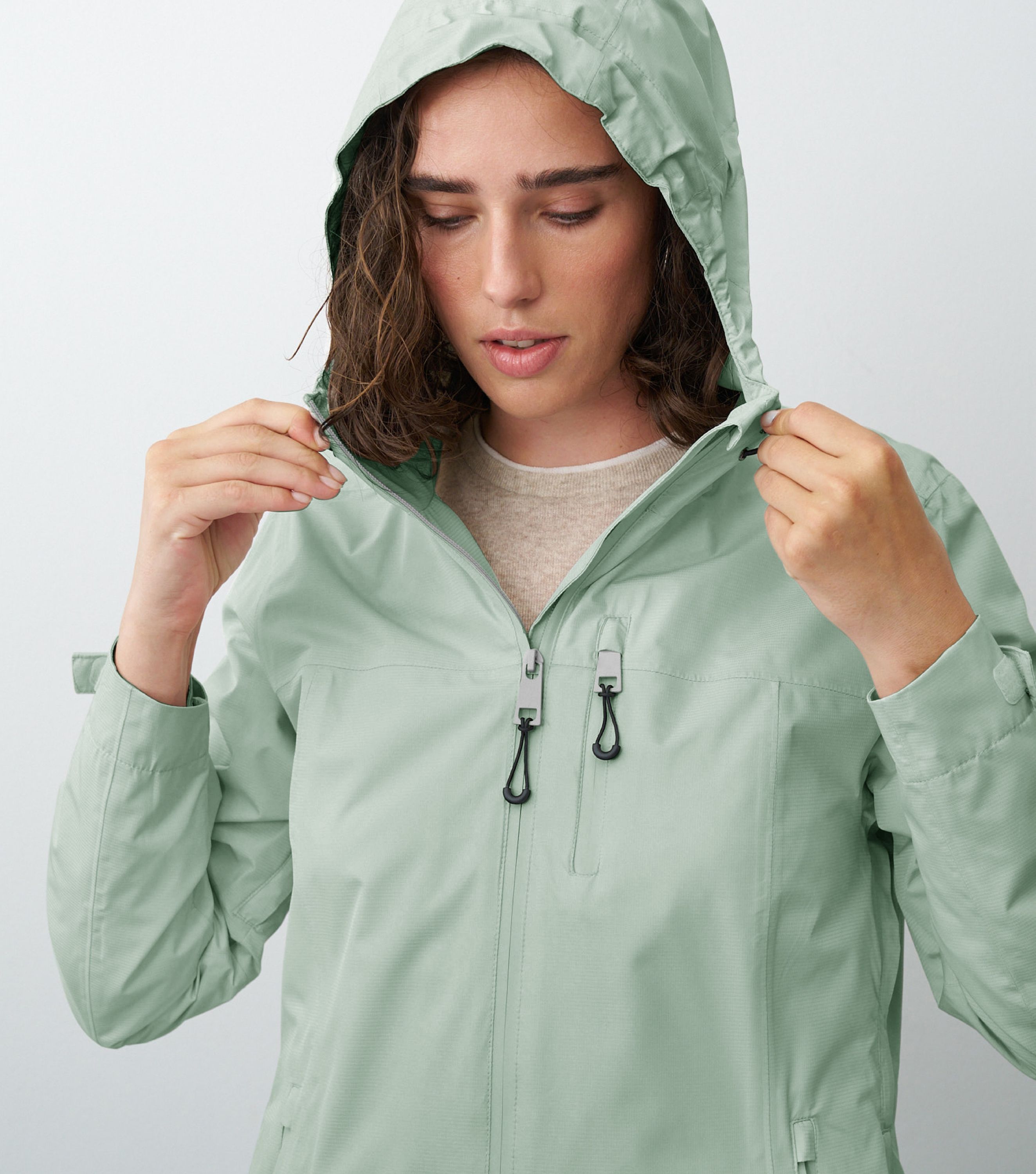 Nahansicht einer Frau die eine grüne Regenjacke trägt und die Kapuze aufhat 