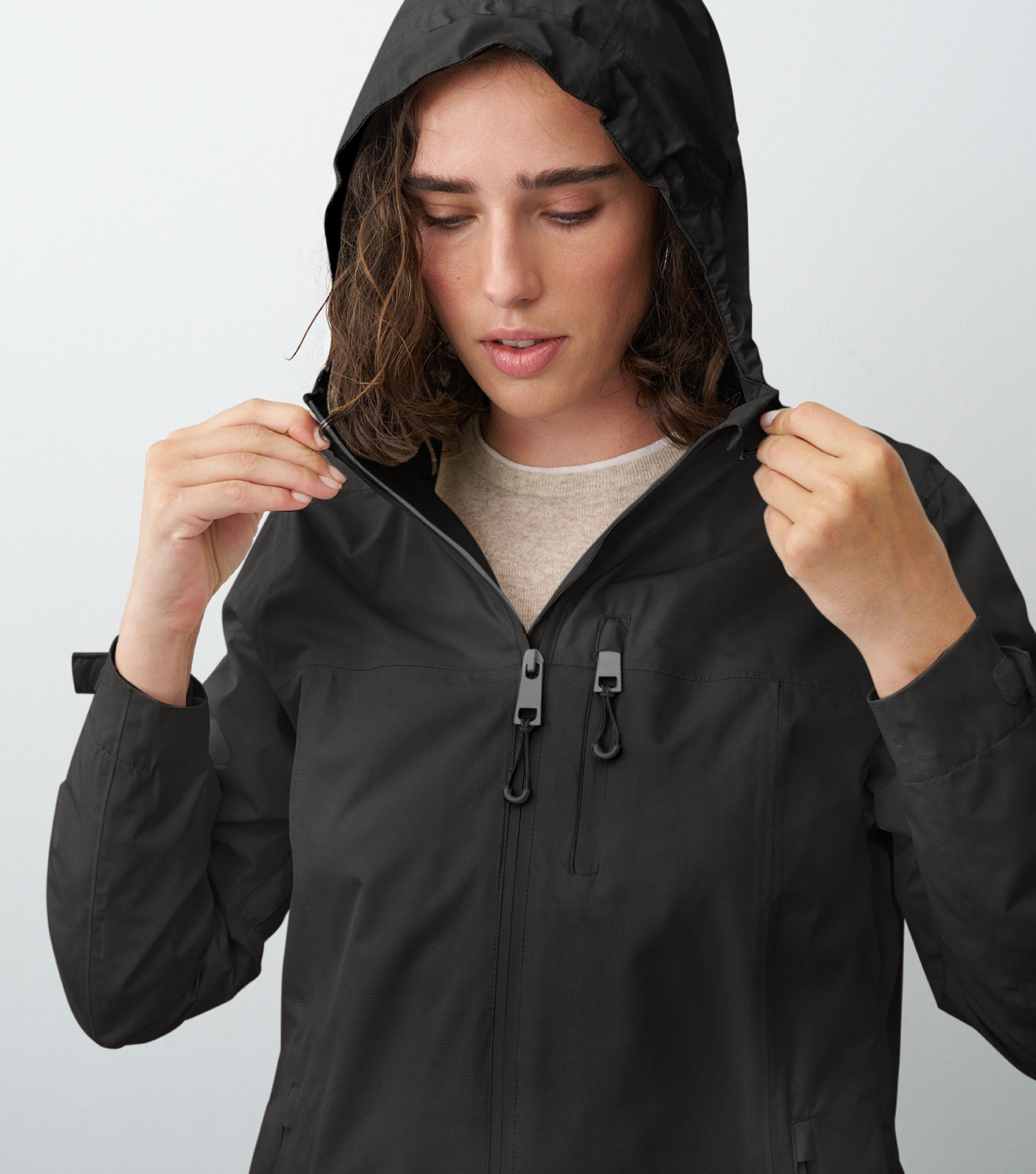 Nahansicht einer Frau die eine schwarze Regenjacke trägt und die Kapuze aufhat 
