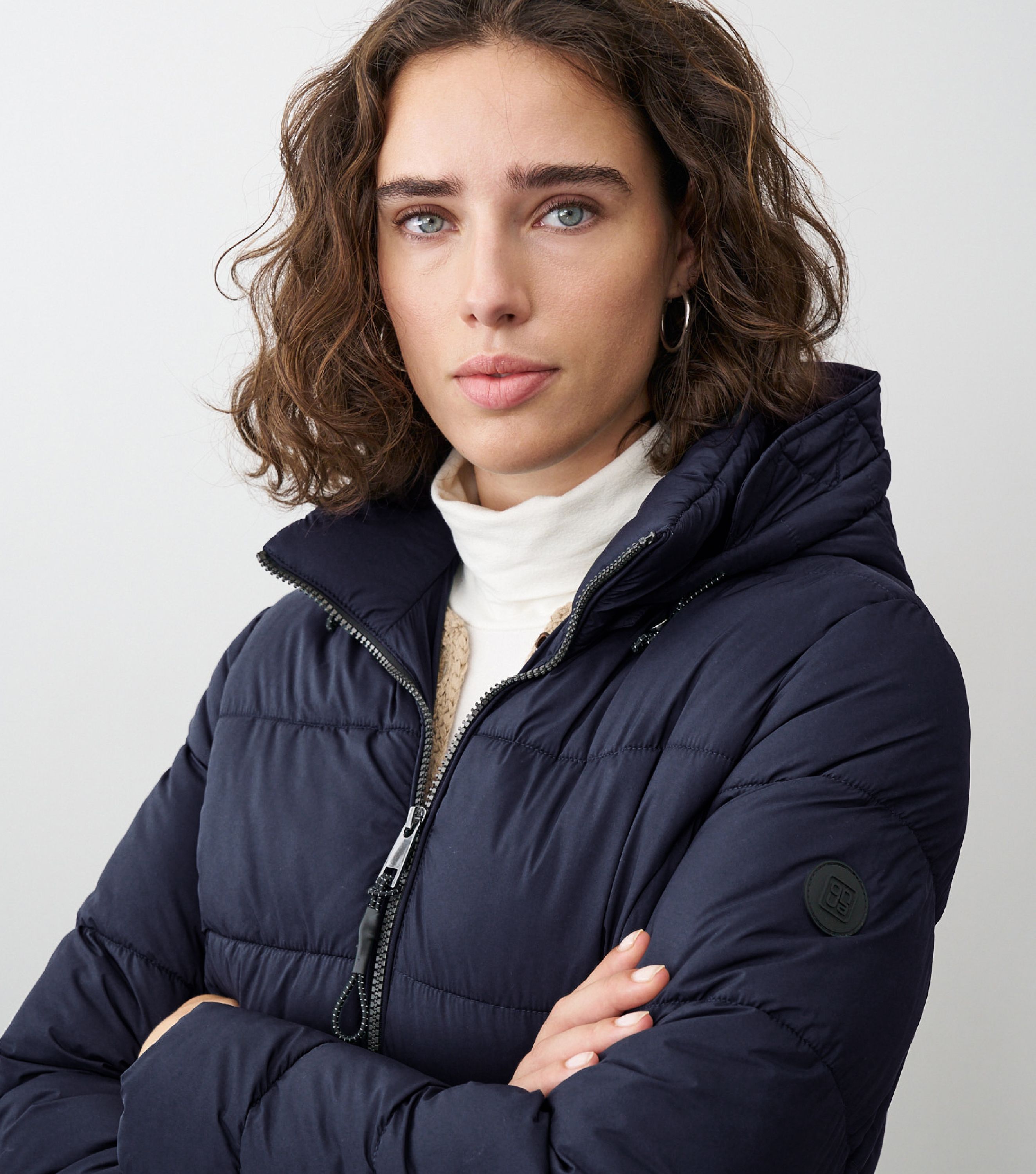 Braunhaarige Frau steht frontal zur Kamera mit blauer Winterjacke 
