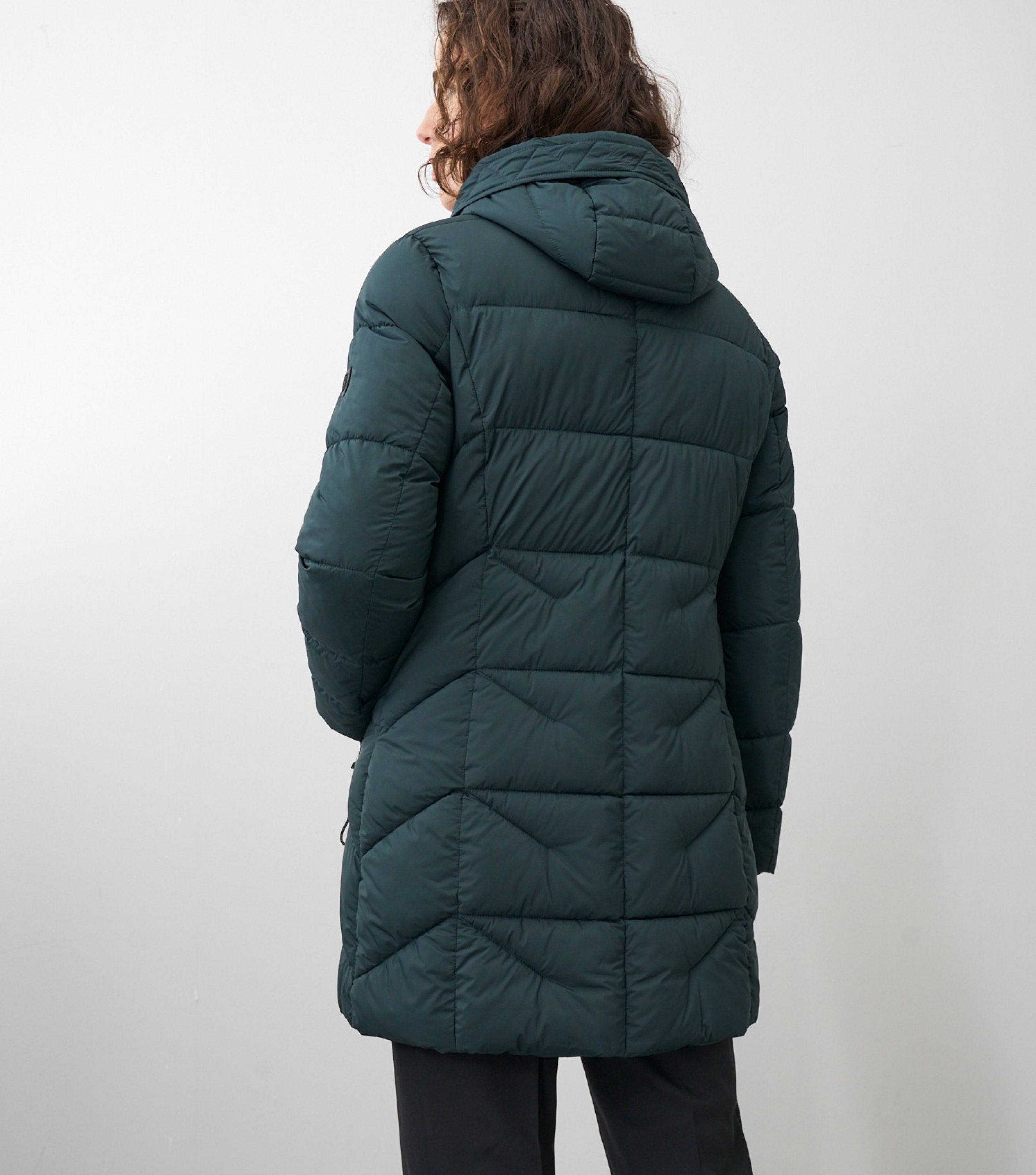 Rückansicht einer braunhaarigen Frau mit einer grünen Winterjacke 